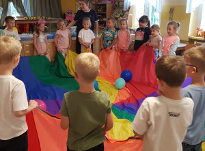 Dzieci chodzą z chustą, na której leżą balony