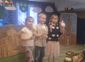 Troje dzieci pokazuje swoje pisanki