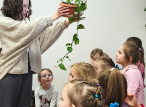 Pani bibliotekarka pokazuje dzieciom roślinę w doniczce