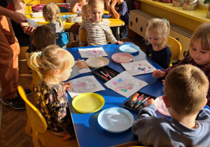 Dzieci przy stoliku robią doświadczenie z papierowym kwiatkiem