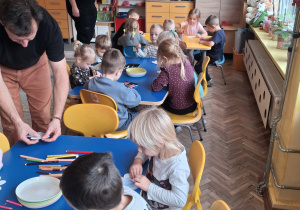Dzieci przy stoliku robią doświadczenie z papierowym kwiatkiem