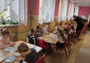 Dzieci przy stoliku robią doświadczenie z papierowym kwiatkiem