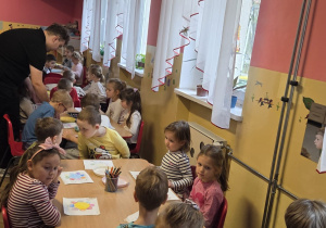 Dzieci przy stoliku robią doświadczenie z papierowym kwiatkiem