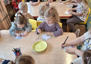 Dzieci przy stoliku robią doświadczenie z papierowym kwiatkiem