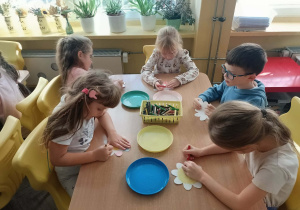 Dzieci przy stoliku robią doświadczenie z papierowym kwiatkiem