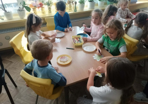 Dzieci przy stoliku robią doświadczenie z papierowym kwiatkiem