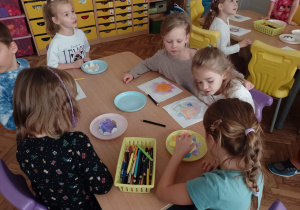 Dzieci przy stoliku robią doświadczenie z papierowym kwiatkiem