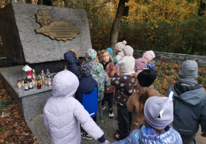 Dzieci stoją przy pomniku "Wilków"