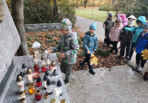 Chłopiec stawia znicz na pomniku "Wilków"