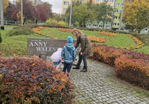 Dwoje dzieci z panią stawiają znicz przy tablicy Anna Walentynowicz