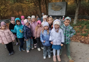 Dzieci stoją przed pomnikiem "Wilków"