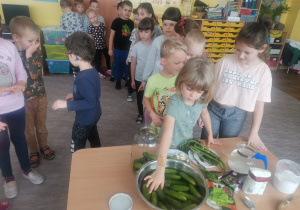 Dzieci wkładają ogórki do słoika