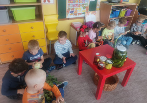 Dzieci oglądają i podają sobie warzywa