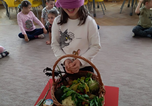 Gabrysia wybiera z koszyka warzywo