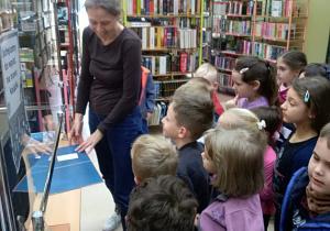 Pani bibliotekarka objaśnia dzieciom, jak wypożycza się książki