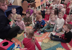 Iluzjonista pokazuje dzieciom sztuczkę z kolorowymi piłeczkami