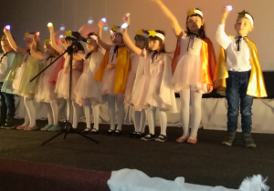 Dzieci występują na scenie ze światełkami w dłoni