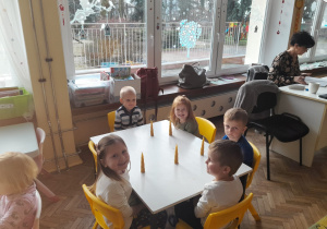 Czworo dzieci z grupy I siedzą przy stoliku ze swoimi świecami
