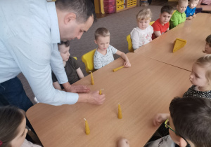 Pan pszczelarz pokazuje dzieciom z grupy VI, jak postawić świecę z wosku