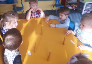 Kilkoro dzieci z grupy II siedzi przy stoliku ze swoimi świecami
