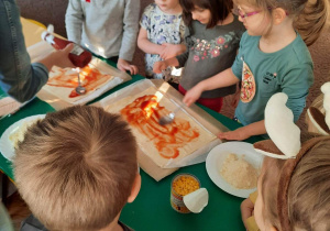 Dzieci z grupy III smarują ciasto na pizzę sosem pomidorowym