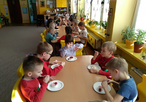 Dzieci z grupy VI jedzą przy stolikach panna cottę