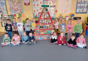 Dzieci z grupy II pokazują piramidę zdrowego żywienia wykonaną przez dzieci z wszystkich grup