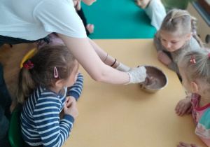 Kilkoro dzieci wącha i ogląda płynną czekoladę