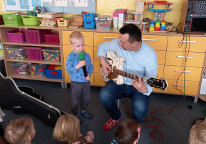 Chłopiec śpiewa a pan Piotr gra na gitarze