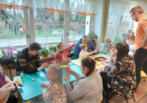 Rodzice z dziećmi przy stolikach robią kogucika