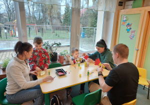Troje rodziców przy stoliku z dziećmi robią kogucika
