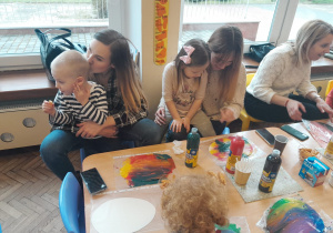 Trzy mamy z dziećmi przy stoliku podczas malowania pisanek