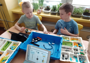 Artur i Kacper przy stoliku budują z klocków Lego