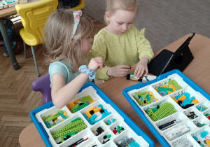 Ola i Maja Z. przy stoliku budują z klocków Lego