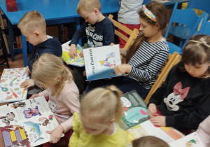 Dzieci siedzą na krzesłach i oglądają książi