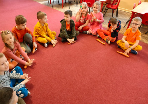 Dzieci z grupy V siedzą na dywanie z marchewkami