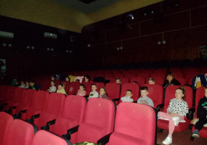Dzieci z grupy IV siedzą w sali kinowe