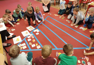 Dzieci na dywanie układają obrazki produktów na piramidzie zdrowia