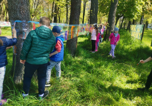 Dzieci malują na folii rozciągniętej miedzy drzewami