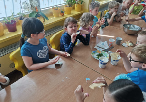 Kilkoro dzieci z grupy VI przy stole degustują sos tzatziki