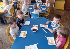 Dzieci z grupy II przy stolikach degustują różne produkty greckie