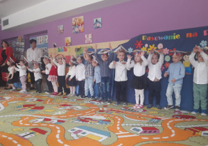 Dzieci stoją jeden obok drugiego i pokazują ruchy do piosenki