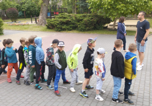 Dzieci ustawione w rzędzie stoją w rozkroku między liną