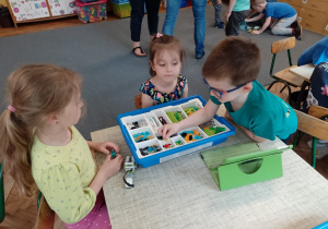 Troje dzieci przy stoliku budują z klocków