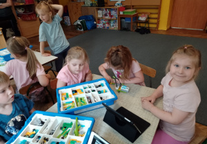 Kilkoro dzieci przy stoliku budują z klocków