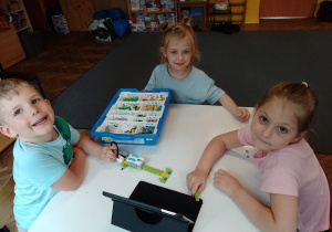 Troje dzieci przy stoliku budują z klocków