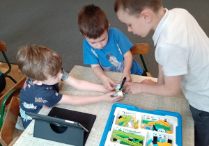 Trzech chłopców przy stoliku budują z klocków