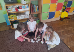 Kilkoro dzieci układa na dywanie puzzle