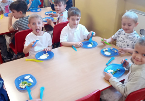 Dzieci z grupy V przy stoliku jedzą deser
