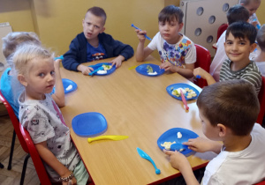 Kilkoro dzieci z grupy V przy stoliku jedzą deser